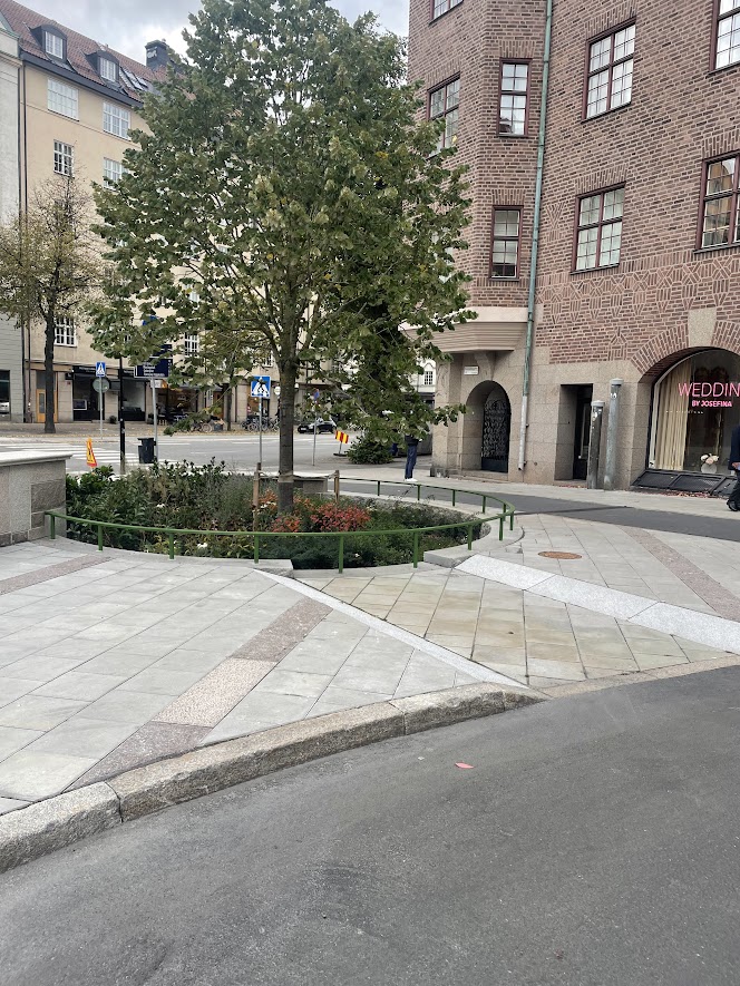 Vy över Östermalmsgatan  i Stocklm med regnhantering med hjälp av  träd och markplattor.