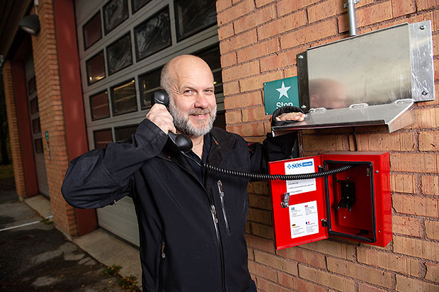 Sven Åkerlund, tekniker på Medelpads Räddningstjänst håller i luren på en nödtelefon på en brandstation