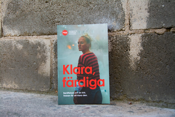 Broschyr med texten Klara färdiga lutad mot en mur.