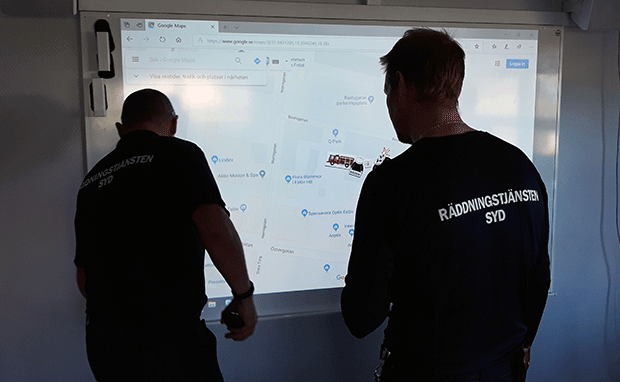Två personer genomför test av räddningstjänstmodul vid en smartboard