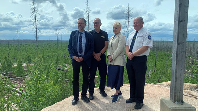 Fyra personer ses stående i helfigur i ett naturreservat.